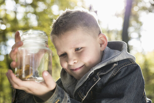 Deutschland, Porträt eines lächelnden kleinen Jungen, der ein Glas mit einem Pilz hält - PDF000808