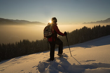 Austria, Tyrol, Schwaz, woman snowshoeing at sunset - MKFF000170