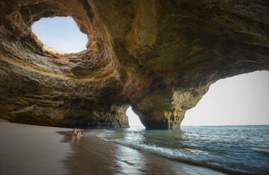Portugal, Strand von Benagil, Höhle, Frau sitzt am Meer - STCF000087