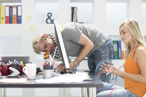 Creative office man helping his colleage with a network cable - ZEF002985