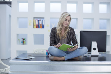 Creative office woman sitting on her desk with a day planner - ZEF003016