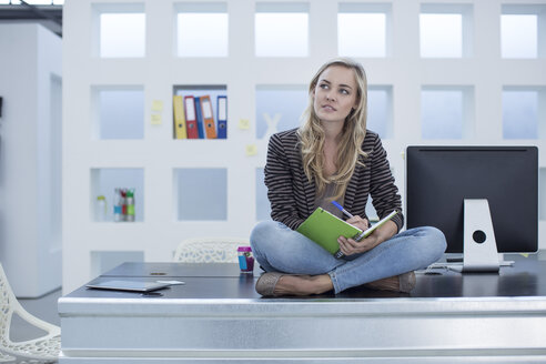Creative office woman sitting on her desk with a day planner - ZEF003017