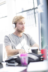 Creative office man working on his computer and wearing a headset - ZEF003086