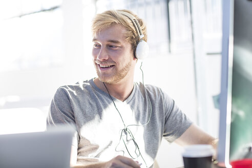 Creative office man working on his computer and wearing a headset - ZEF003087