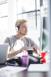 Creative office man working on his computer and wearing a headset - ZEF003088