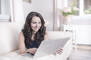 Portrait of smiling woman using laptop in living room - VTF000400