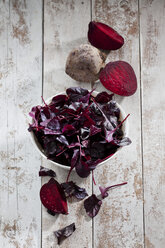 Beetroot and bowl of leaves on wood - CSF024618