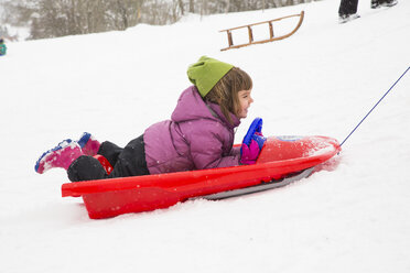 Germany, Swabian mountains, little girl lying on sledge - LVF002910