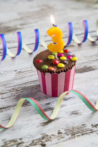 Geburtstagsmuffin mit Schokoladenknöpfen und brennenden Kerzen, lizenzfreies Stockfoto