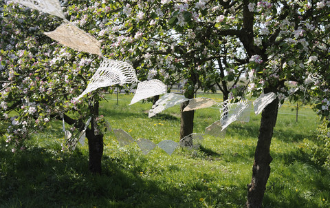 Deutschland, Hamburg, Teile von alten gehäkelten Tischdecken hängen zwischen blühenden Apfelbäumen, lizenzfreies Stockfoto