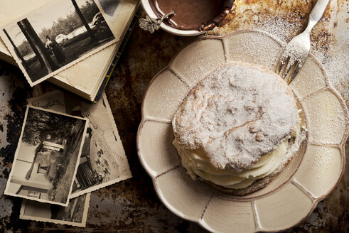 Aufgeschnittenes Brötchen mit Schlagsahne, eine Tasse heiße Schokolade und alte Fotografien - CSTF000882