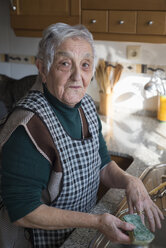 Porträt einer älteren Frau beim Geschirrspülen in der Küche - RAEF000052