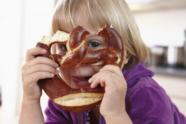 Little girl looking through pretzel - RHF000557