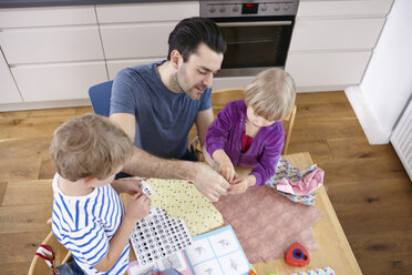 Vater bastelt mit Sohn und Tochter in der Küche - RHF000562