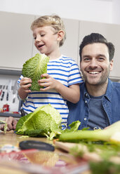 Father preparing food in kitchen with son - RHF000574