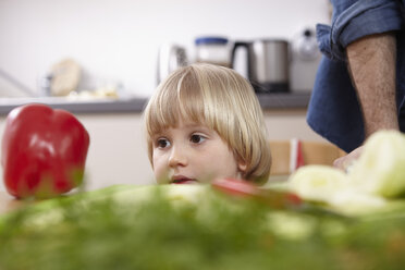 Kleines Mädchen in der Küche schaut auf rote Paprika - RHF000581