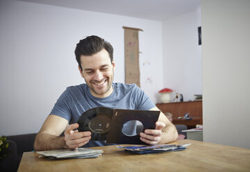 Mann sitzt am Tisch mit alten Schallplatten - RHF000614