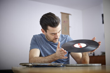 Mann sitzt am Tisch mit alten Schallplatten - RHF000616