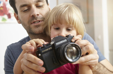 Father explaining analogue camera to daughter - RHF000626