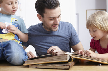 Father looking at photo album with kids - RHF000628