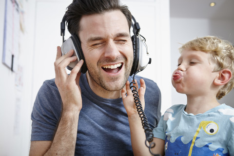 Vater und Sohn beim Musikhören mit Kopfhörern, lizenzfreies Stockfoto