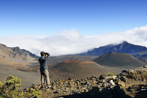 USA, Hawaii, Maui, Haleakala, man taking picture of volcanic landscape with cinder cones - BRF001112