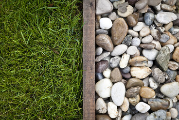 Gras und Kieselsteine in einem Garten voneinander getrennt - DISF001401