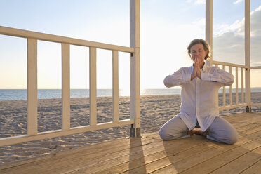 Portugal, Algarve, Frau macht Yoga-Übungen am Strandhaus bei Sonnenuntergang - MSF004495