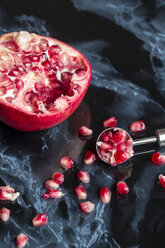 Pomegranate, pomegranate seeds and cutter on black marble - SARF001426