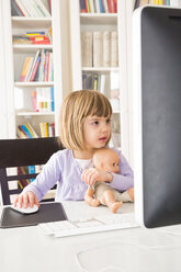 Portrait of little girl with doll spending time at computer - LVF002925