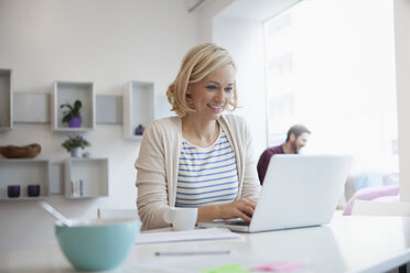 Porträt einer Frau, die im Büro zu Hause mit einem Laptop arbeitet - RBF002465