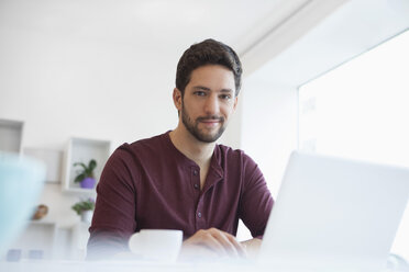 Porträt eines Mannes, der im Büro zu Hause mit einem Laptop arbeitet - RBF002475