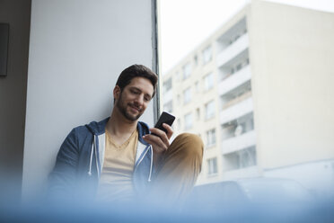 Smiling man reading SMS - RBF002478