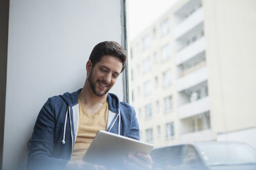 Portrait of smiling man using digital tablet - RBF002481