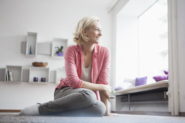 Woman sitting on carpet at living room - RBF002496