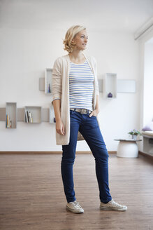 Woman standing in modern living room - RBF002519