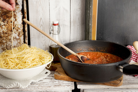 Spaghetti Bolognese, Spaghetti auf dem Teller und Sauce Bolognese in der Pfanne, Spaghetti zum Knabbern, lizenzfreies Stockfoto