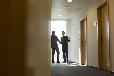 Businesspeople in corridor shaking hands - WESTF020848