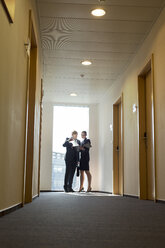 Business people discussing documents in corridor - WESTF020850