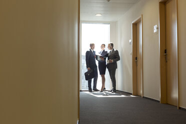 Business people discussing documents in corridor - WESTF020856