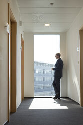 Businessman looking out of window - WESTF020864