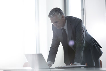 Businessman in office looking at laptop - WESTF020977