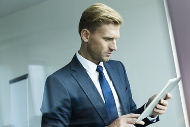 Businessman holding digital tablet, looking down - WESTF020964