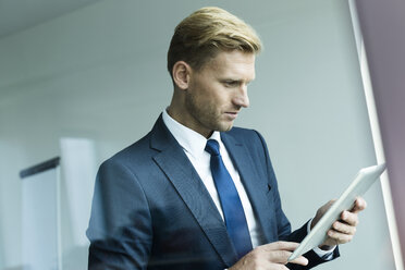 Geschäftsmann hält digitales Tablet und schaut nach unten - WESTF020964