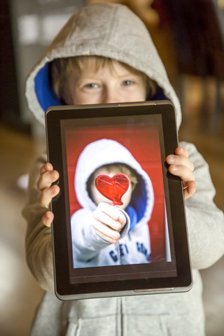 Junge zeigt digitales Tablet mit Foto von sich selbst, lizenzfreies Stockfoto