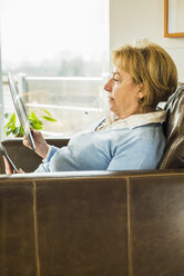 Ältere Frau zu Hause mit Blick auf die Platte - UUF003466