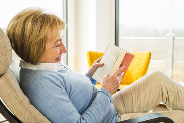 Ältere Frau zu Hause beim Lesen eines Buches - UUF003472