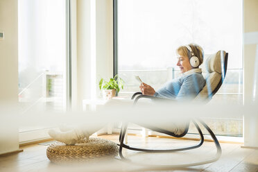 Senior woman at home with headphones and digital tablet - UUF003475