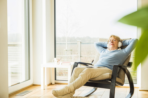 Ältere Frau zu Hause beim Entspannen mit Kopfhörern, lizenzfreies Stockfoto