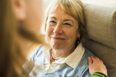 Smiling grandmother looking at adult granddaughter - UUF003493